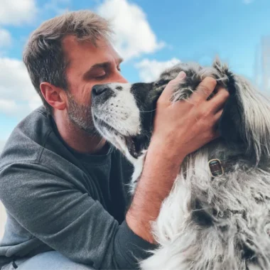 Man hugging his white and black dog