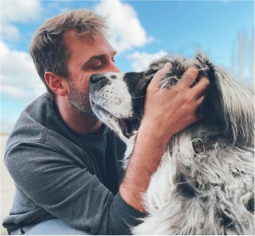 Man hugging big dog with their faces touching